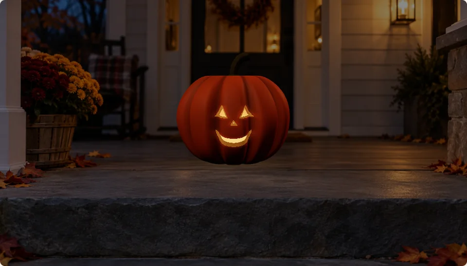 An orange pumpkin with carved triangular eyes and a glowing smile on a warmly lit porch at night.